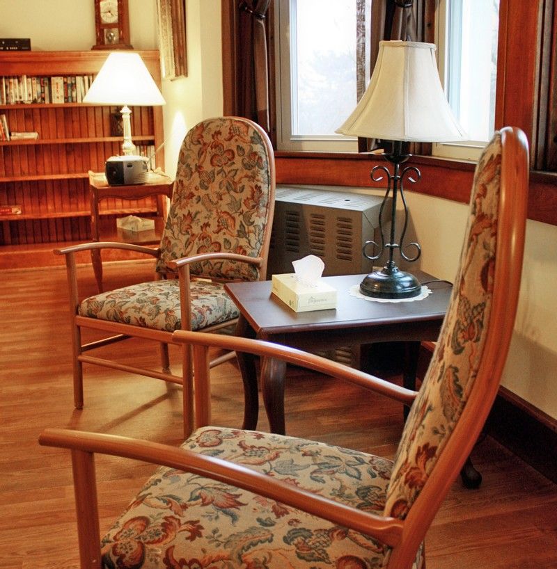 A cozy living room setup with patterned chairs, a small table, and lamps for lighting.