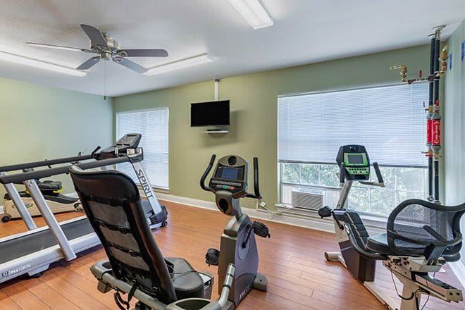 A well-equipped fitness room featuring a treadmill, stationary bike, and other cardio machines.