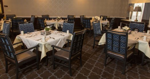 An elegantly set dining area in a restaurant with neatly arranged tables and chairs.