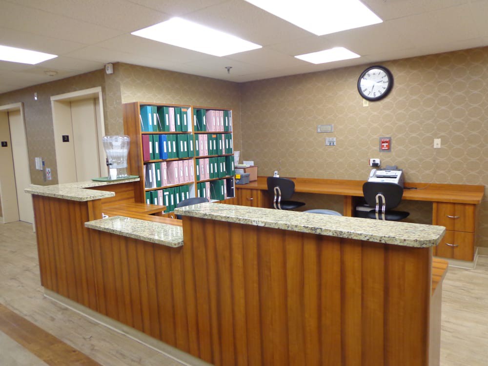 A tidy reception area with a wooden desk and shelves filled with files.