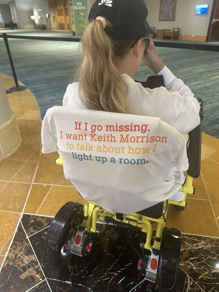 Person in a wheelchair wearing a shirt with printed text.