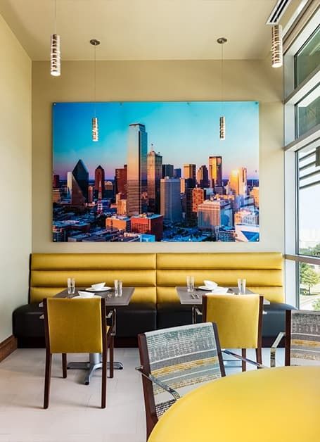A restaurant interior featuring a large cityscape artwork and modern dining furniture.