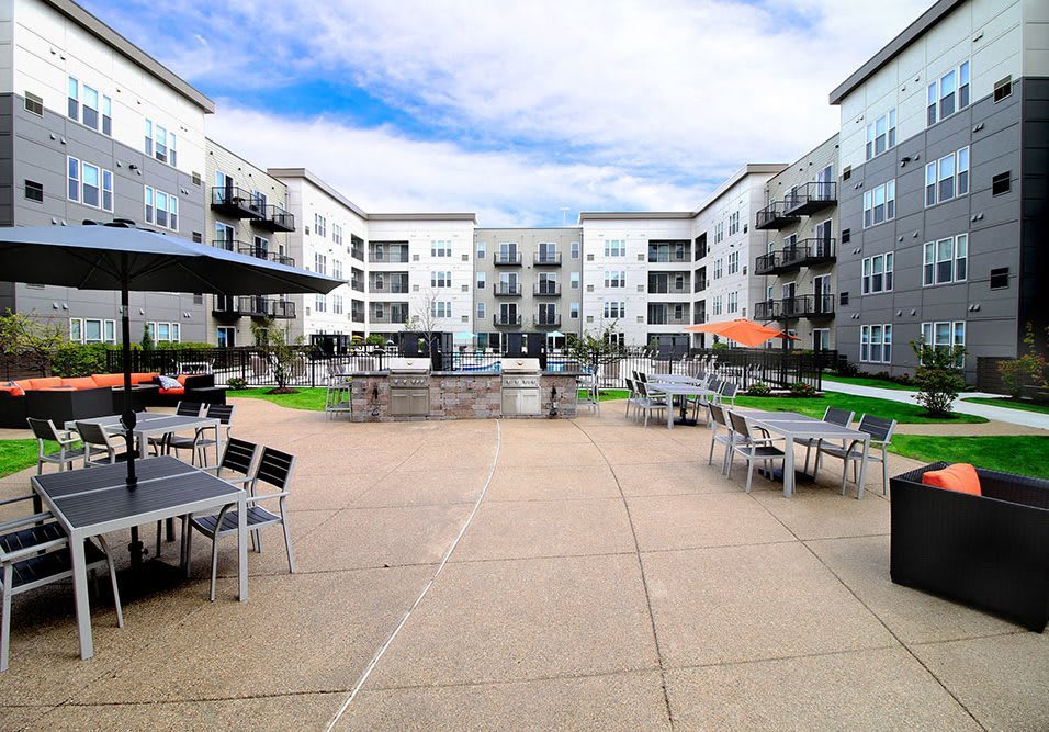A modern apartment complex featuring a spacious courtyard with outdoor seating and amenities.