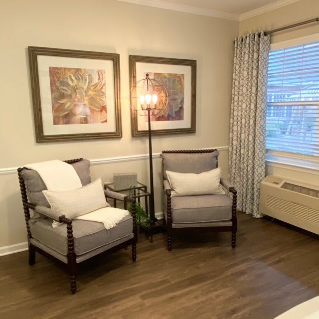 Cozy seating area with armchairs and artwork in a bright living space.