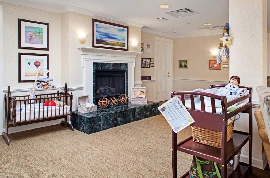 A cozy nursery room featuring a fireplace, crib, and artwork on the walls.