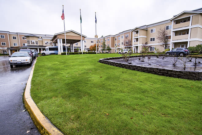 A hotel building with a manicured lawn and multiple flags at the entrance.