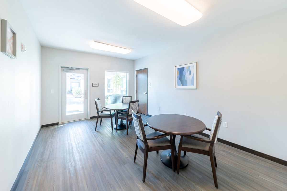 A modern dining area with round tables and chairs, featuring ample natural light.