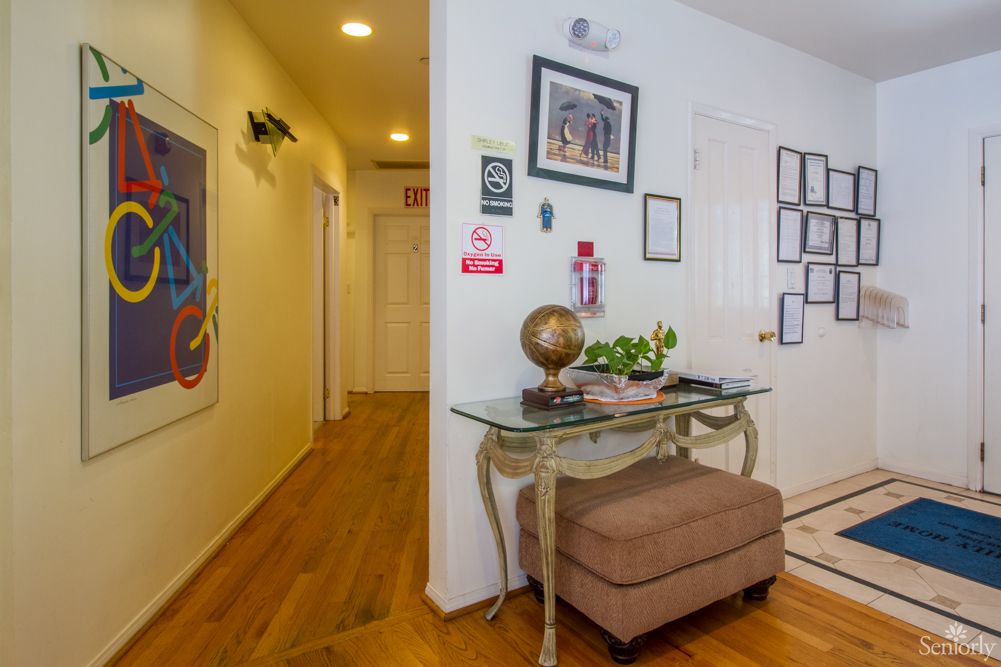 A welcoming hallway with wooden floors, adorned with artwork and a decorative table featuring a globe and plants.
