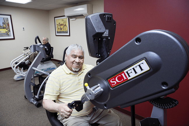 An elderly person using exercise equipment in a fitness room.