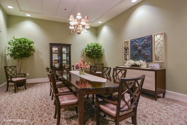 A well-decorated dining room with a long table, chairs, and a chandelier.