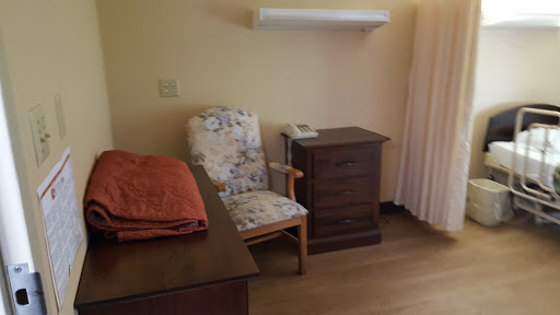 A cozy room featuring a floral chair and a wooden bedside table.