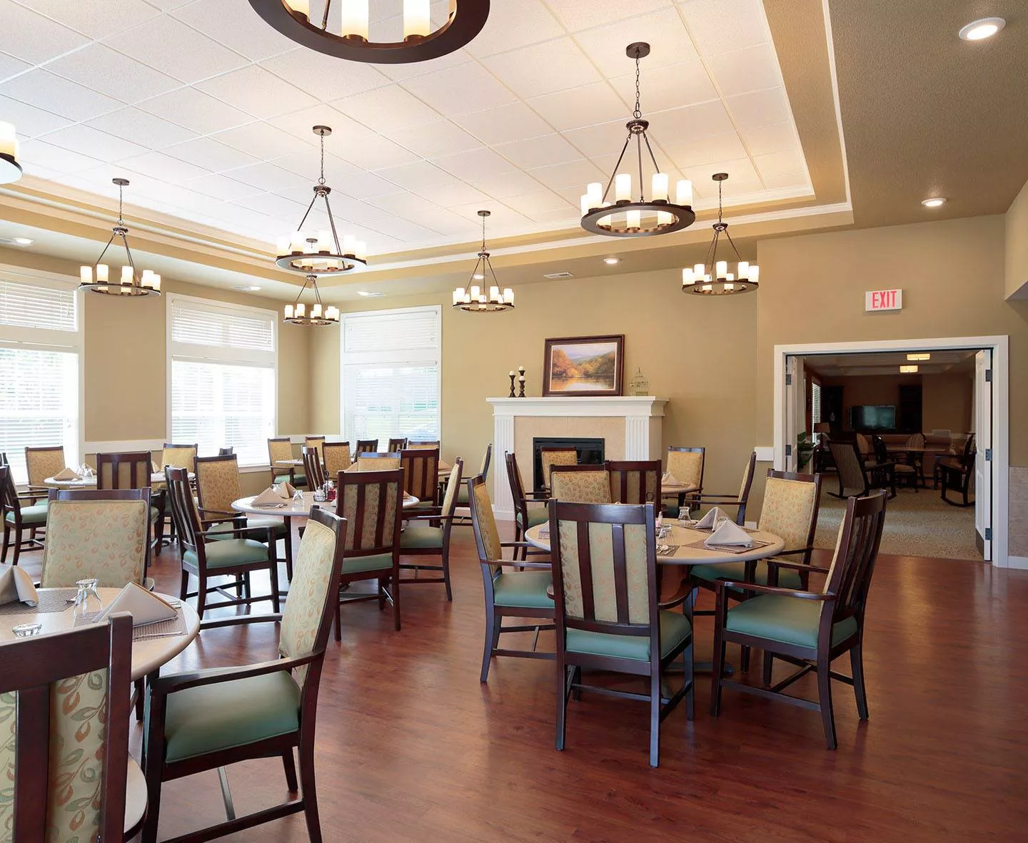 An elegant dining room with multiple tables and chairs, adorned with chandeliers.