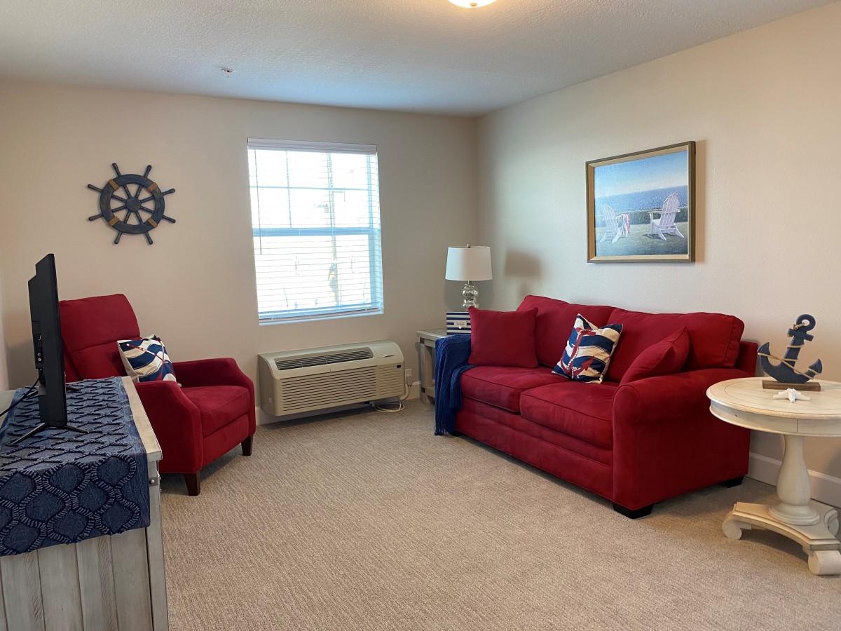 A cozy living room with nautical-themed decor and red furniture.
