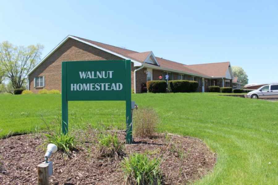 A building with a sign reading 'Walnut Homestead' in front of a well-maintained lawn.