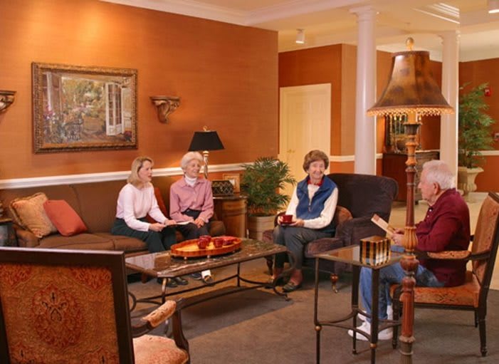A group of people sitting in a cozy living room, engaged in conversation.