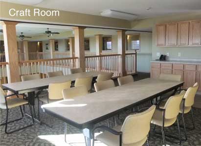 A spacious meeting room with a long conference table and several chairs, featuring natural light from windows.