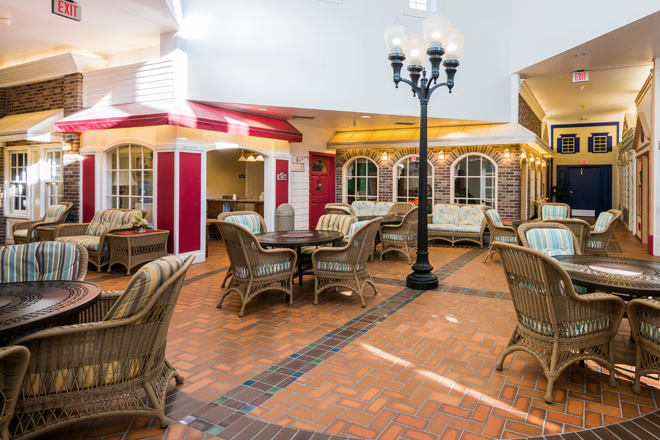 A cozy indoor seating area with wicker furniture and a vintage lamppost on a brick floor.
