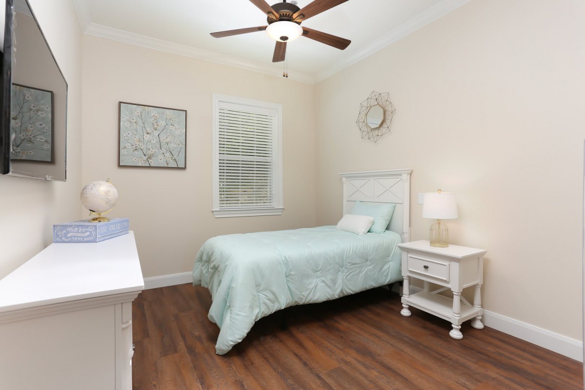 A cozy bedroom with a single bed, wooden flooring, and soft lighting.
