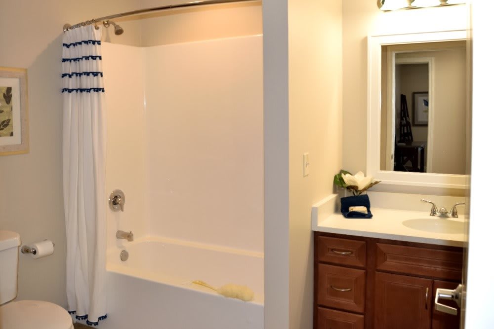 A clean and simple bathroom with a bathtub and shower curtain next to a sink and mirror.