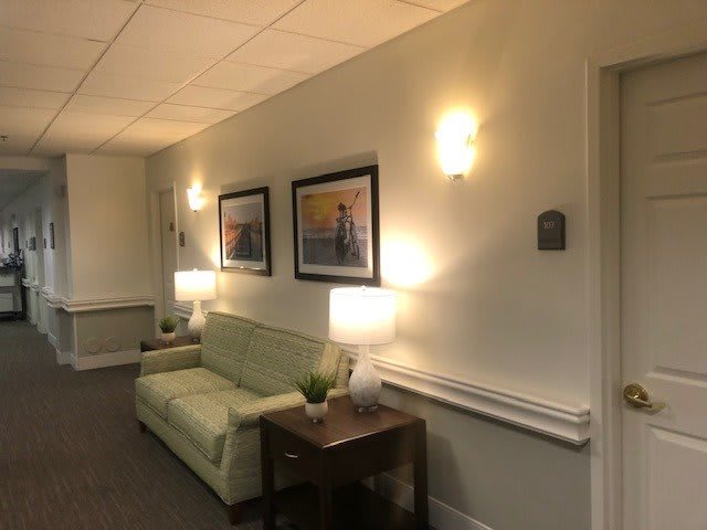 A cozy hallway with a green sofa, soft lighting, and framed artwork on the walls.