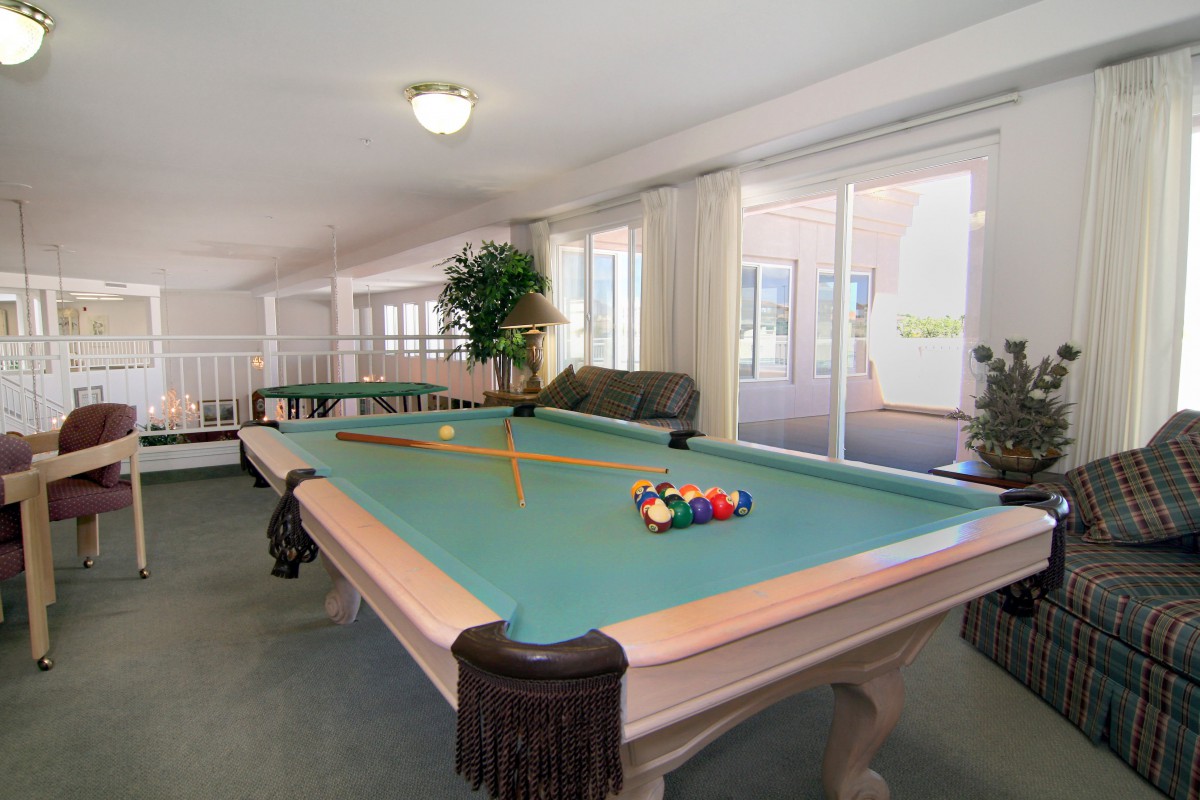 A spacious game room featuring a billiards table with cues and pool balls.