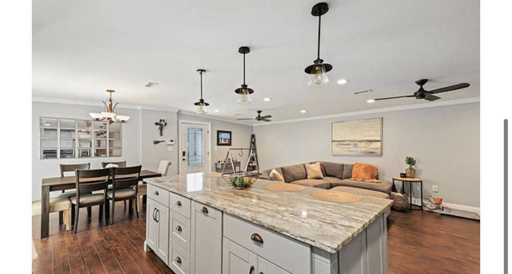A modern open floor plan combining a kitchen and living room, featuring a large kitchen island with pendant lighting and a comfortable seating area.
