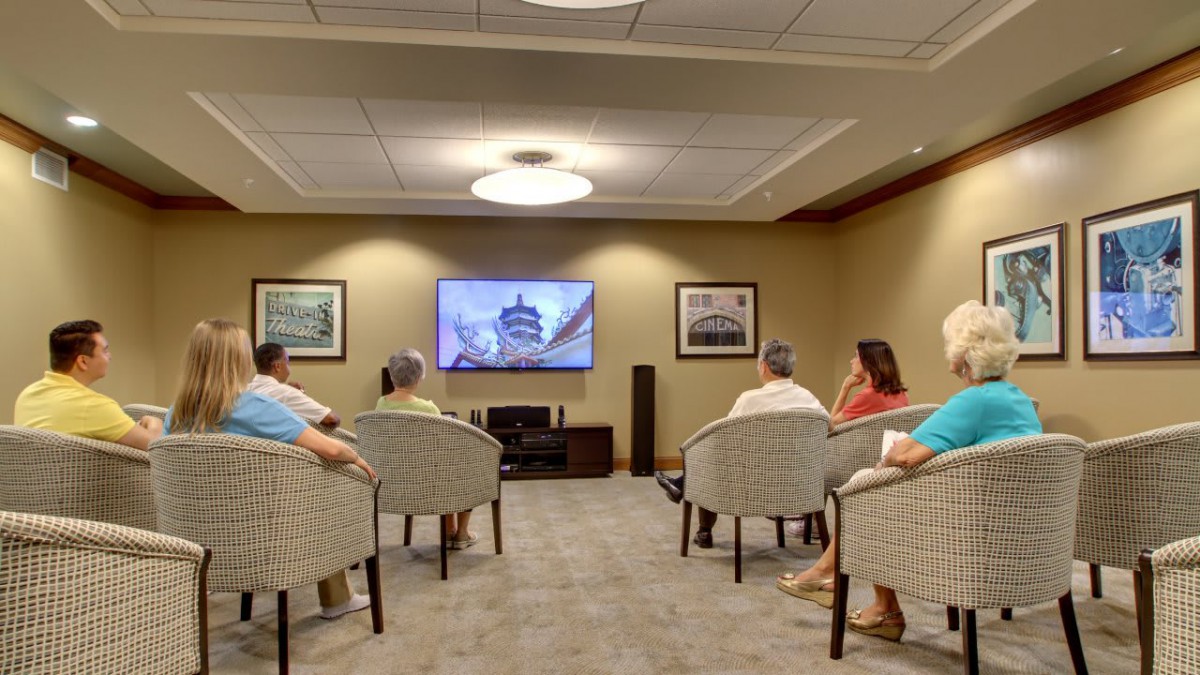 A group of seniors sitting in a comfortable television room watching a show together.