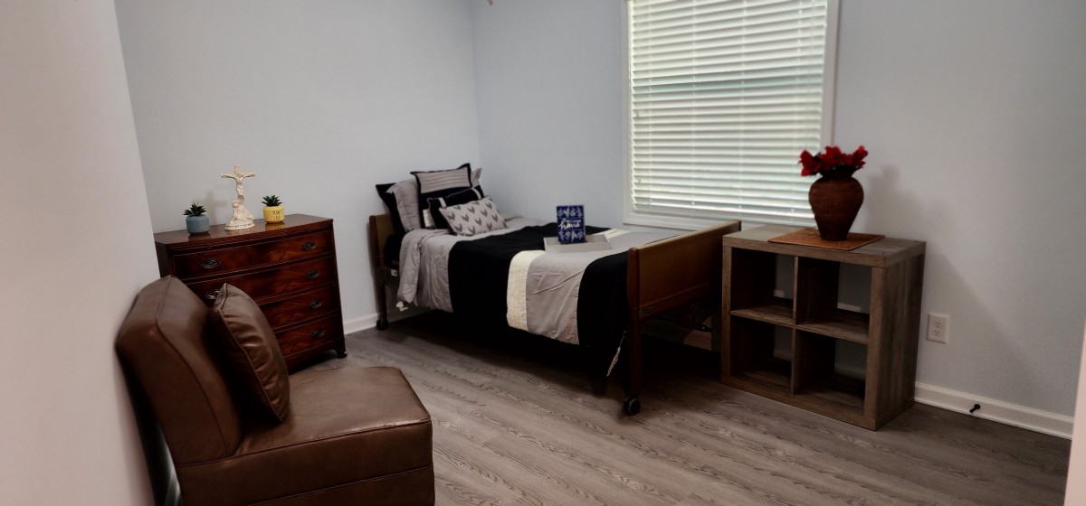 A minimalist bedroom with a single bed, desk, and dresser.