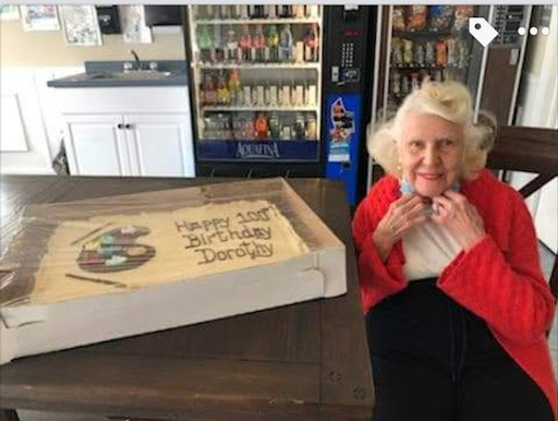 A joyful elderly woman celebrating with a beautifully decorated cake.