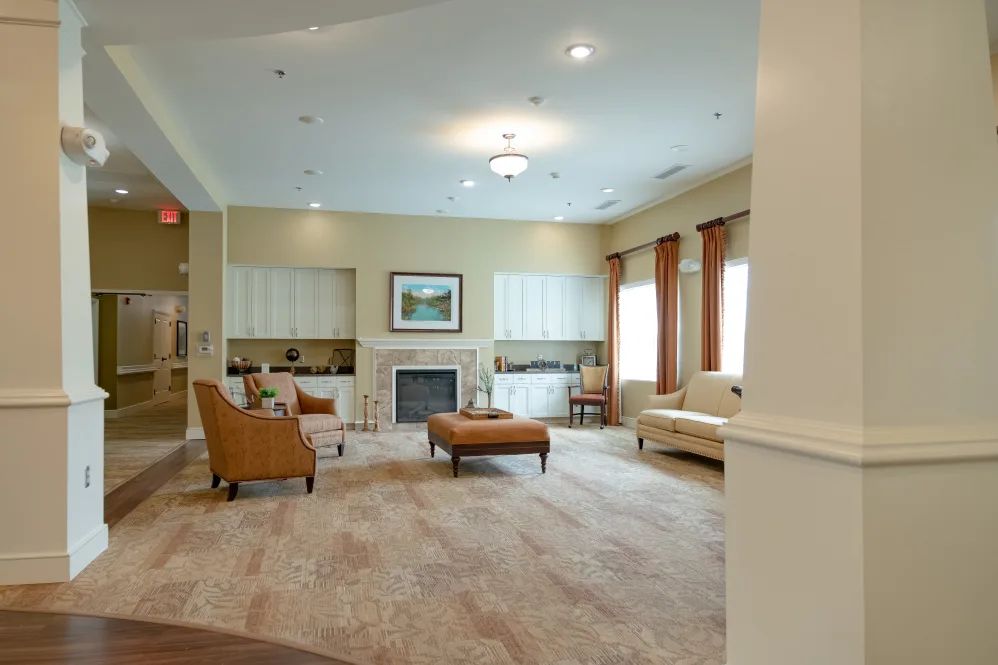 A spacious living room with elegant furnishings, featuring a fireplace and ample natural light.