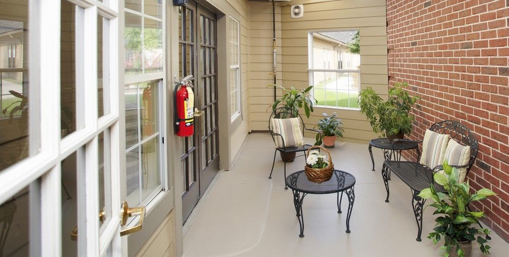 A cozy patio with a table, chairs, and plants, featuring a fire extinguisher mounted on the wall.