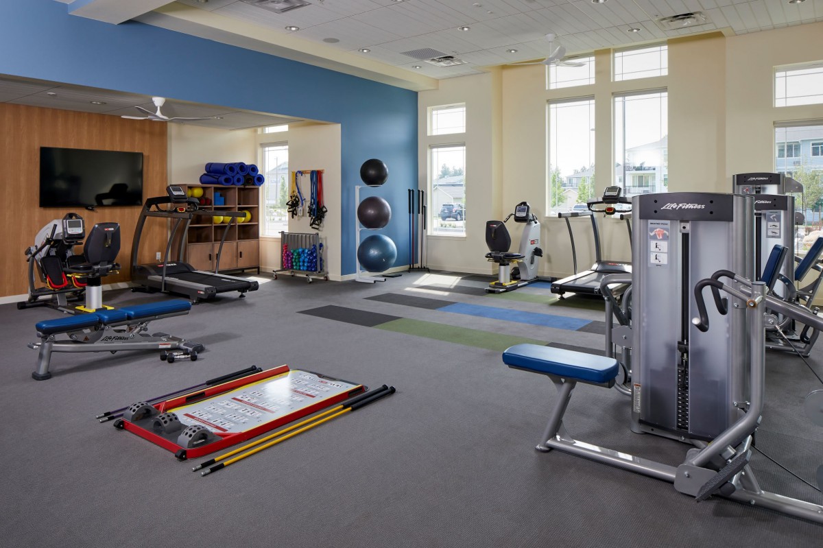 A spacious gym filled with various exercise equipment and workout areas.