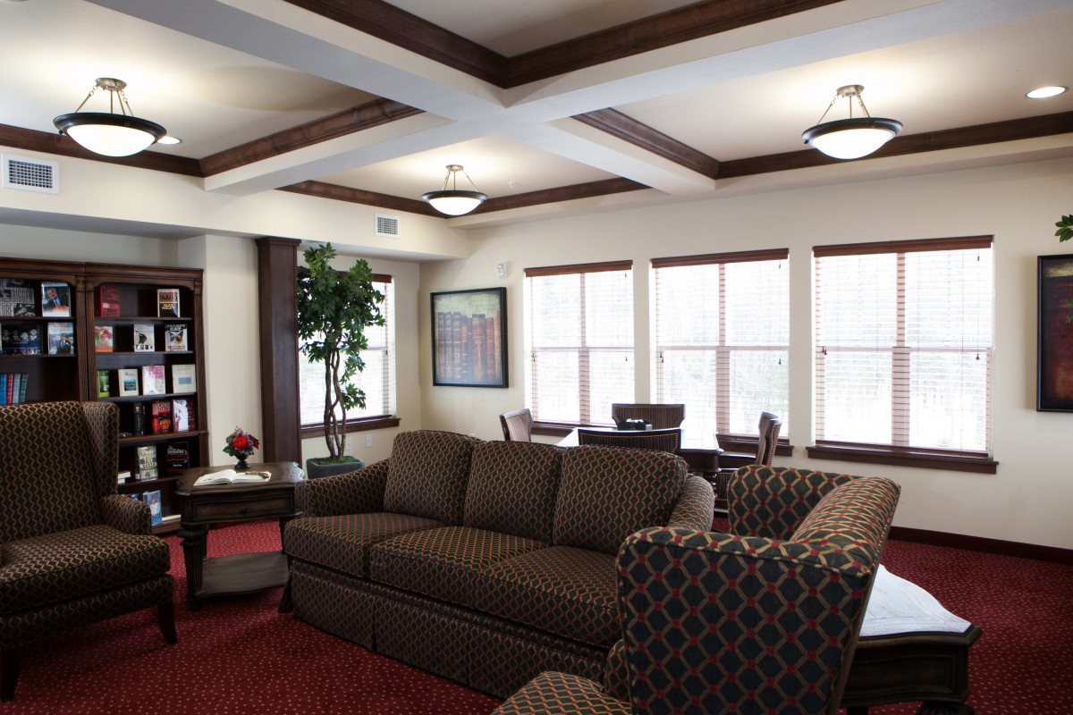 A cozy living room with a sofa, armchairs, and natural light from multiple windows.
