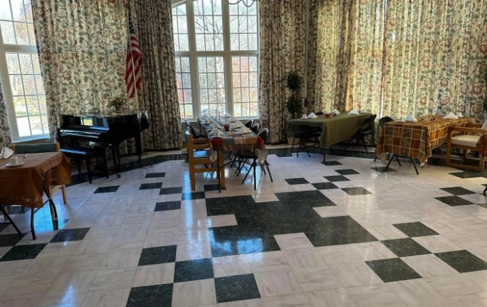 A spacious room with large windows, patterned floor, and arranged furniture.