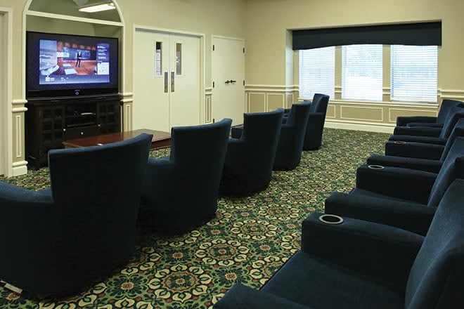 A small theater room with comfortable seating and a TV screen.