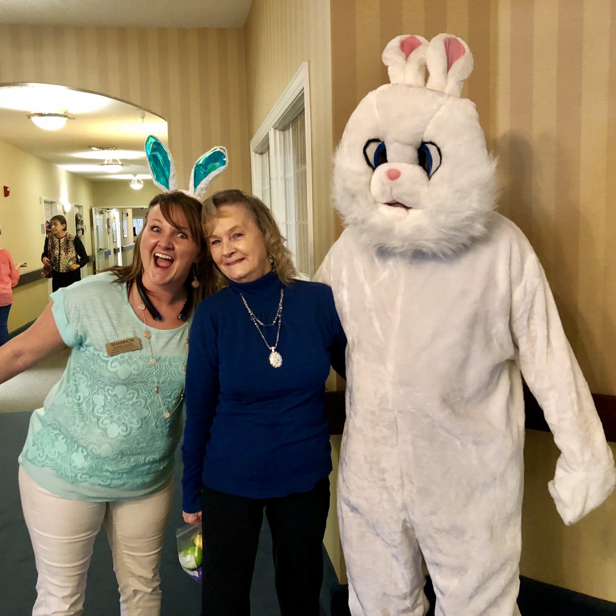 A group of people smiling with someone dressed as the Easter Bunny.