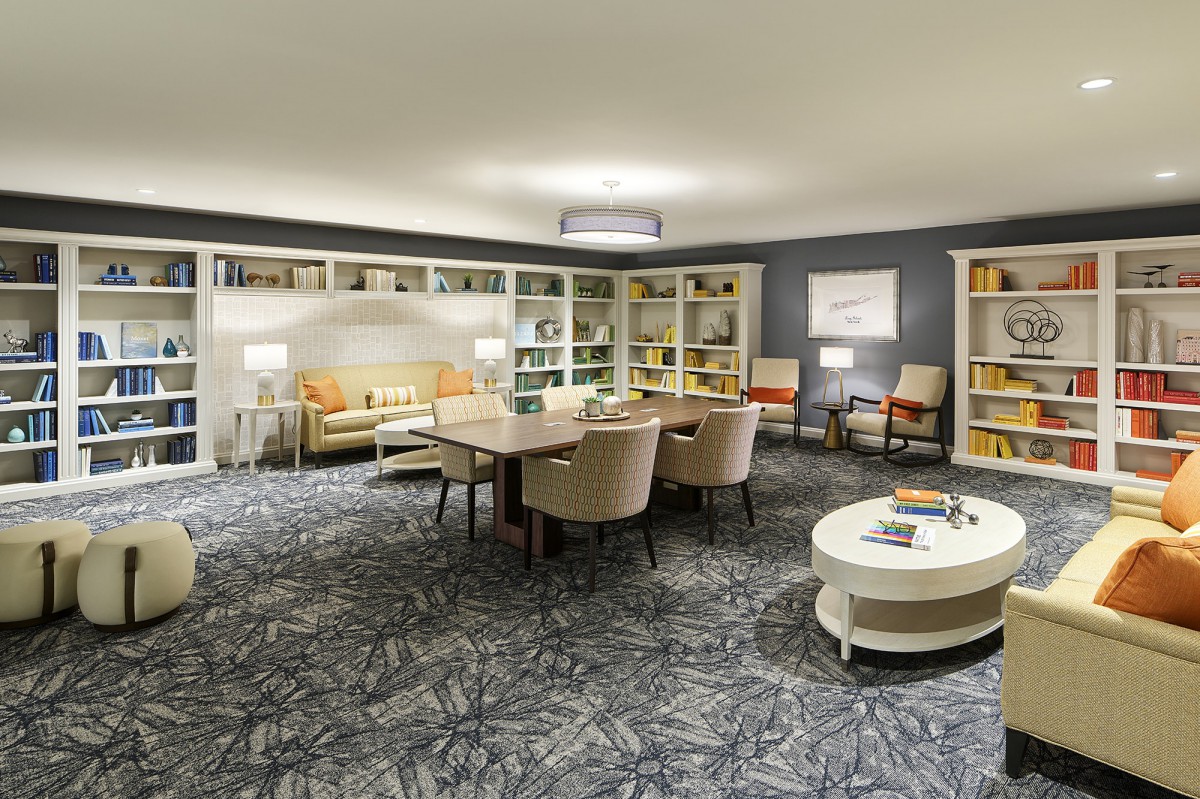 A cozy living room with comfortable seating, bookshelves, and a central table.