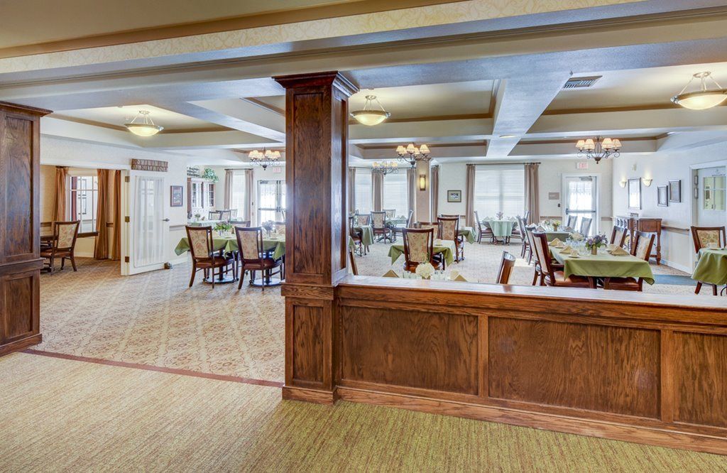A spacious dining area featuring wooden decor, multiple tables and chairs, with ample natural light from large windows.