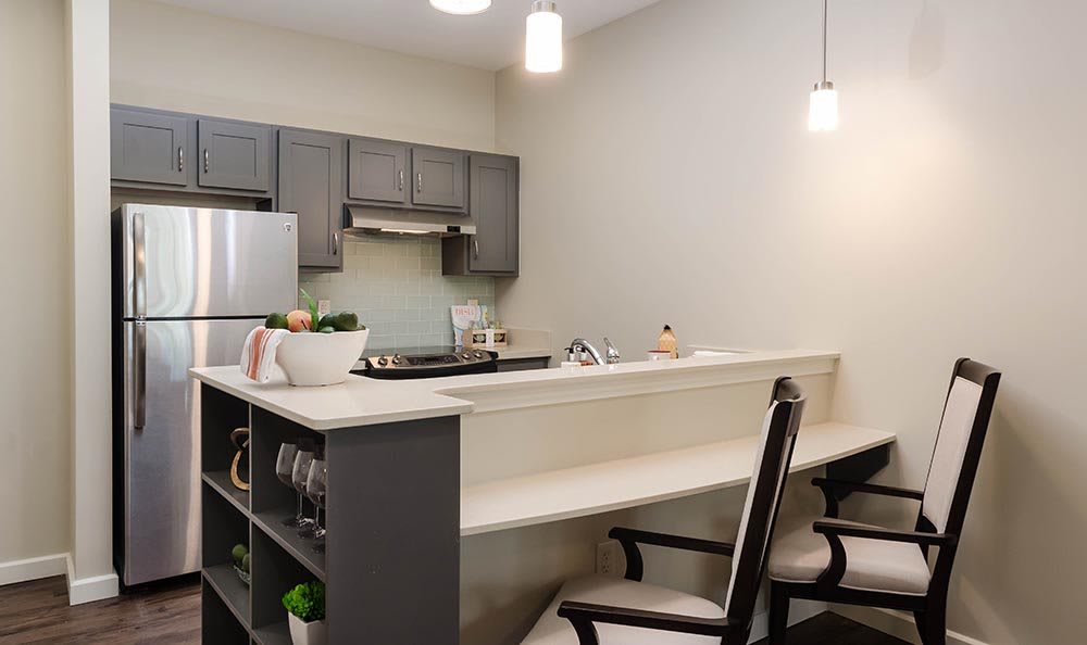 A modern kitchen with sleek cabinets, countertops, and bar stools.