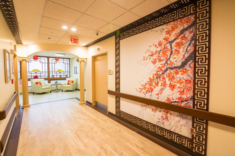 A warmly lit hallway featuring a large wall art piece with floral design, leading to a cozy seating area.