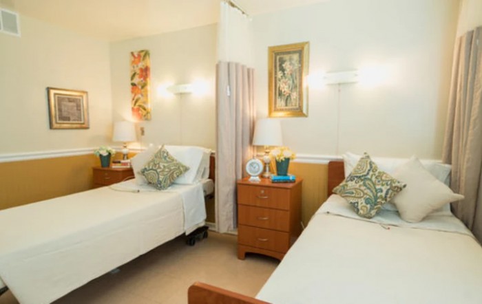A cozy bedroom with two neatly arranged beds, decorative pillows, lamps, and wall art.