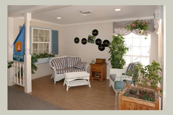 A cozy living room with vintage decor, featuring a striped sofa, record-themed wall art, and abundant indoor plants.