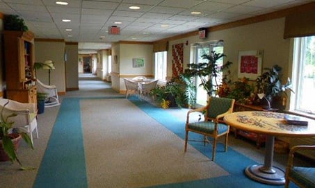 A well-lit hallway with seating areas and indoor plants.