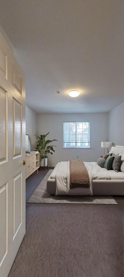 A cozy bedroom with neutral decor, featuring a neatly made bed, a large potted plant, and natural light coming through the window.