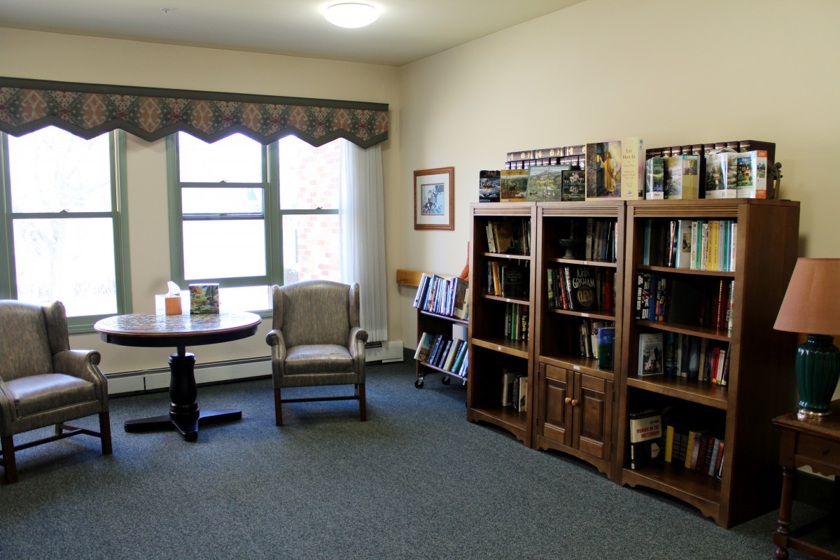 A cozy reading room with bookshelves, a chair, and a small table by the window.
