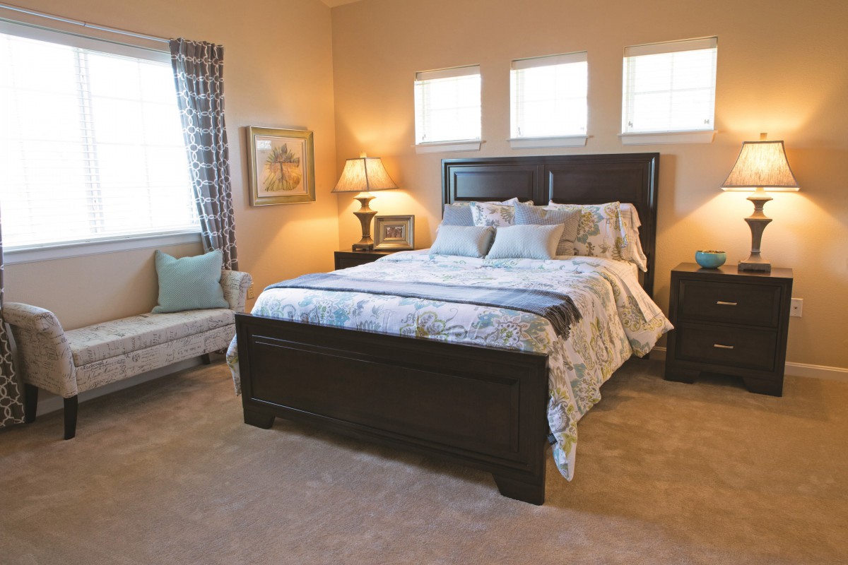 A cozy bedroom with a neatly made bed, bedside lamps, and elegant decor.