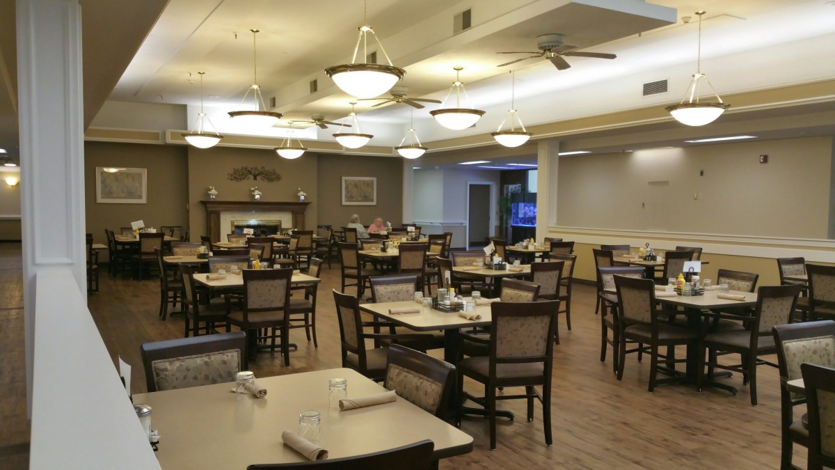 An empty restaurant dining area with neatly arranged tables and chairs under warm lighting.