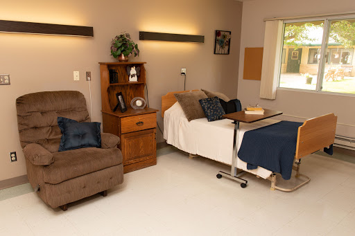 A cozy hospital room designed for patient comfort, featuring a bed, recliner, and essential medical furnishings.