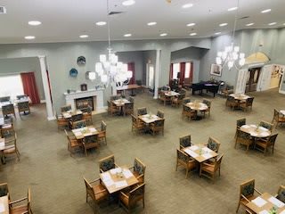 A spacious dining room with neatly arranged tables and chairs, modern lighting fixtures, and a cozy fireplace.