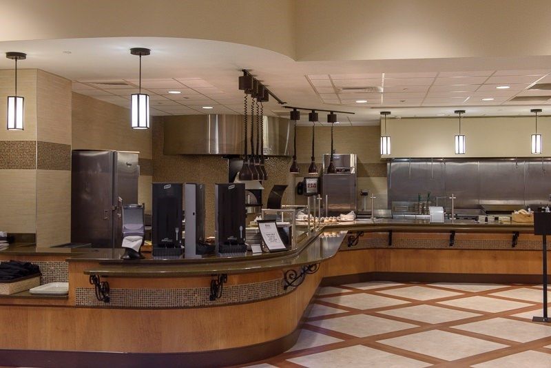 An empty modern cafeteria with a sleek counter and overhead lighting.